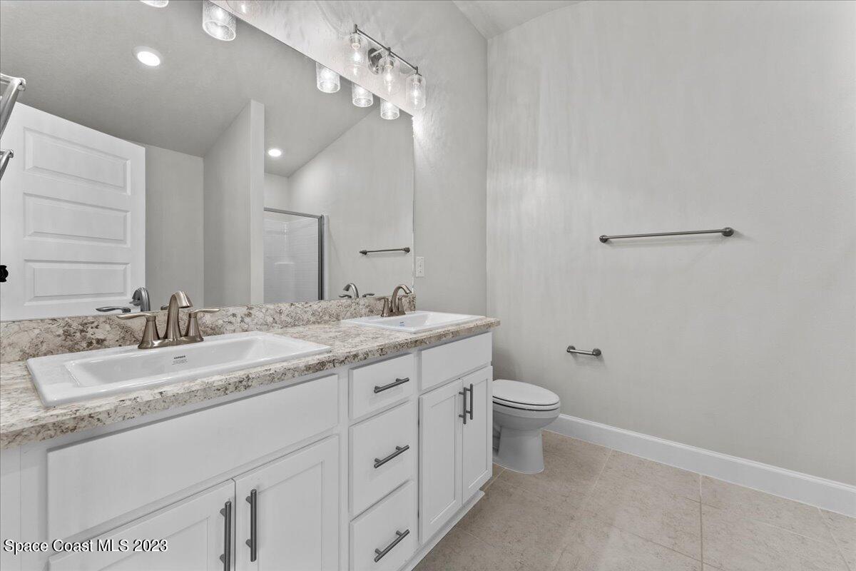 1341 Tupelo Circle Cocoa, FL 32926 - Photo 18 of 27 a bathroom with a granite countertop sink a toilet and a mirror