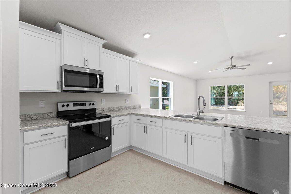 1341 Tupelo Circle Cocoa, FL 32926 - Photo 10 of 27 a kitchen with granite countertop white cabinets sink and stainless steel appliances