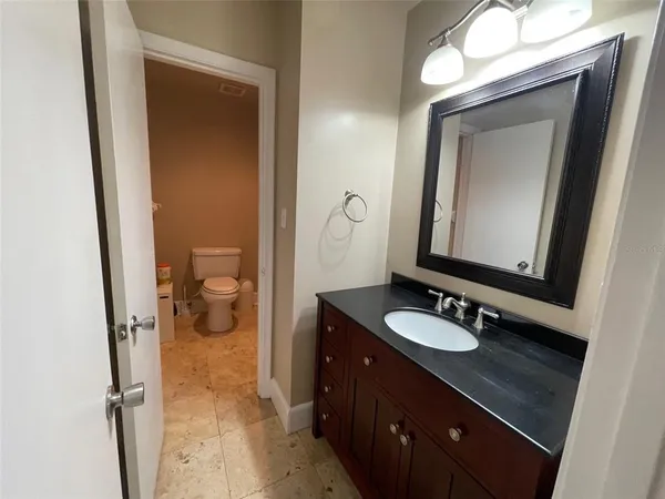 a bathroom with a granite countertop sink a toilet and a mirror