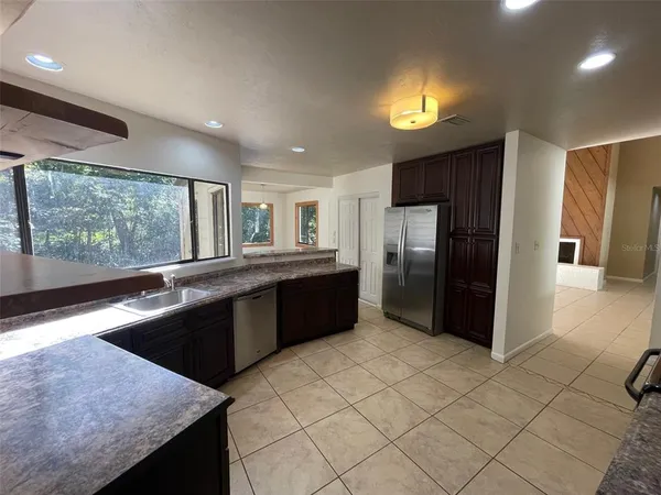 a large kitchen with a large counter top stainless steel appliances a sink cabinets and a counter top