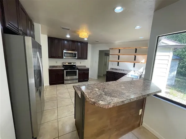 a kitchen with stainless steel appliances granite countertop a refrigerator a stove and a sink