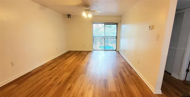 a view of an empty room with wooden floor and a window
