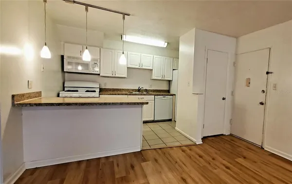 a kitchen with kitchen island white cabinets and wooden floor