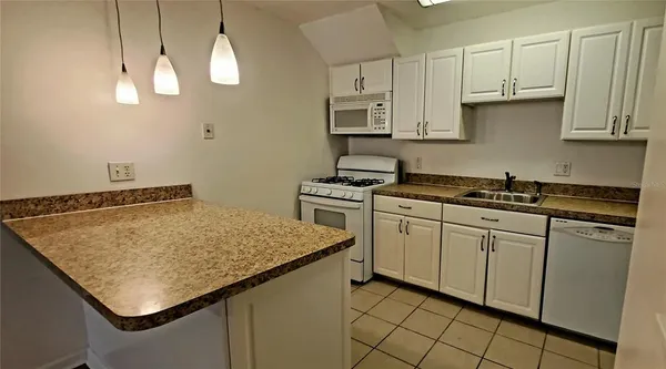 a kitchen with stainless steel appliances granite countertop a sink dishwasher and white cabinets with wooden floor