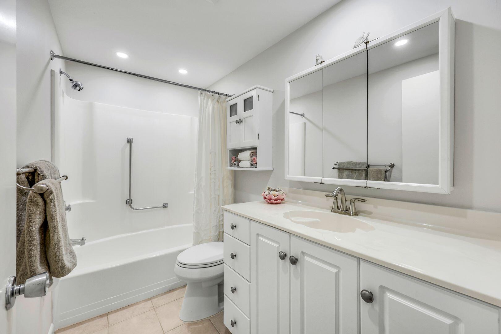60 West Pelican Street, Unit 407 Naples, FL 34113 - Photo 17 of 26 a bathroom with a sink a toilet and a large mirror