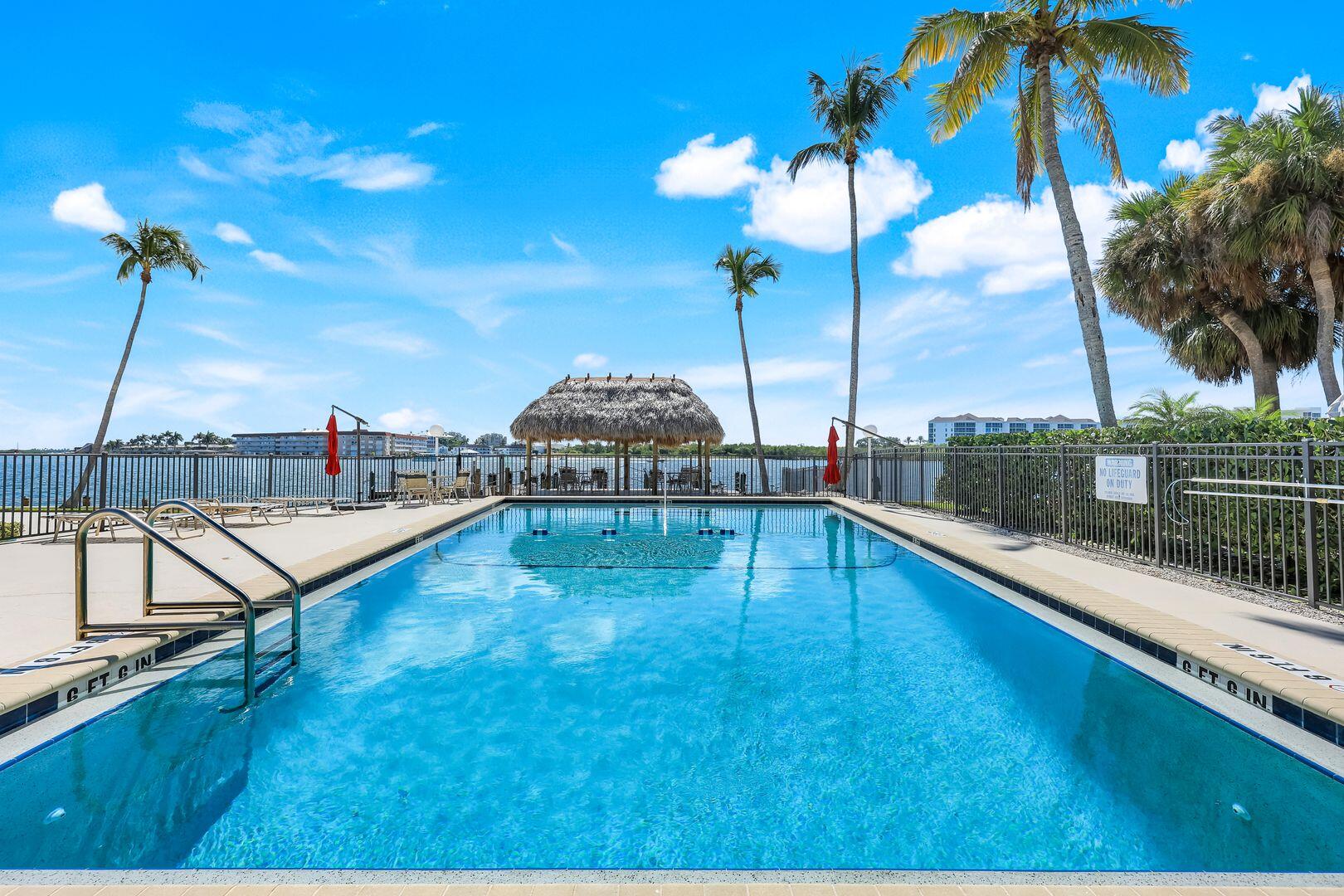 60 West Pelican Street, Unit 407 Naples, FL 34113 - Photo 23 of 26 a view of a swimming pool with a lounge chairs