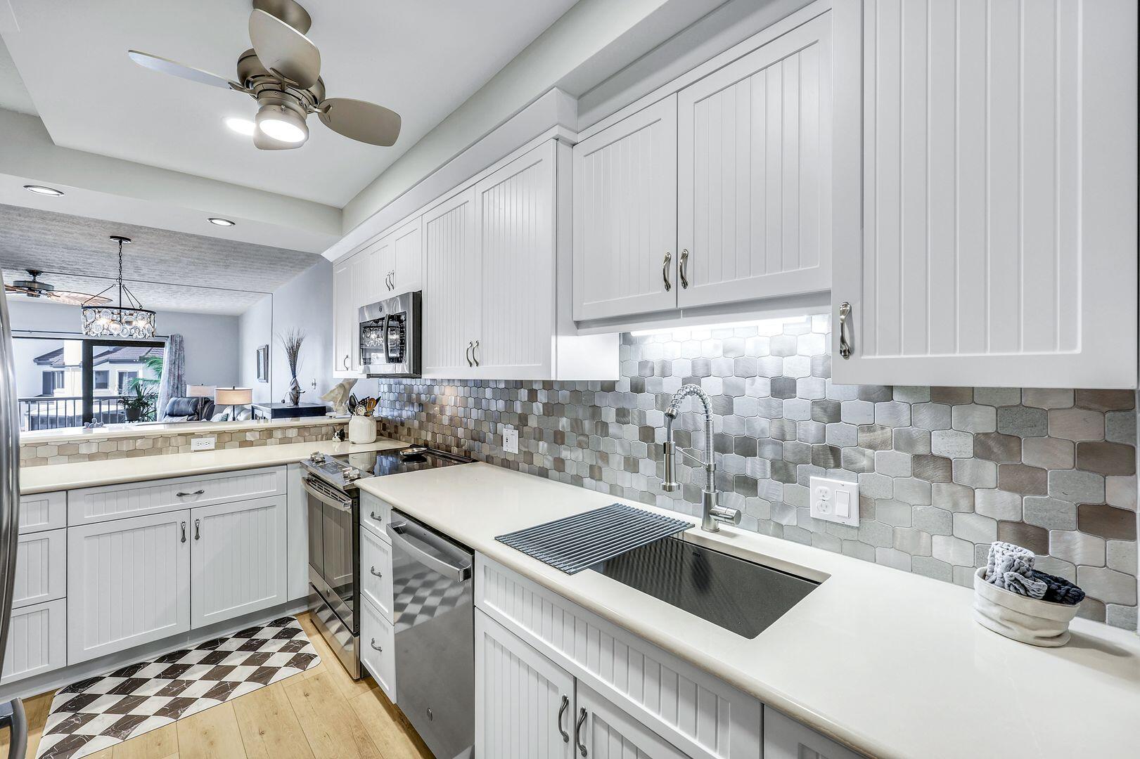 60 West Pelican Street, Unit 407 Naples, FL 34113 - Photo 9 of 26 a kitchen with a sink stove and cabinets