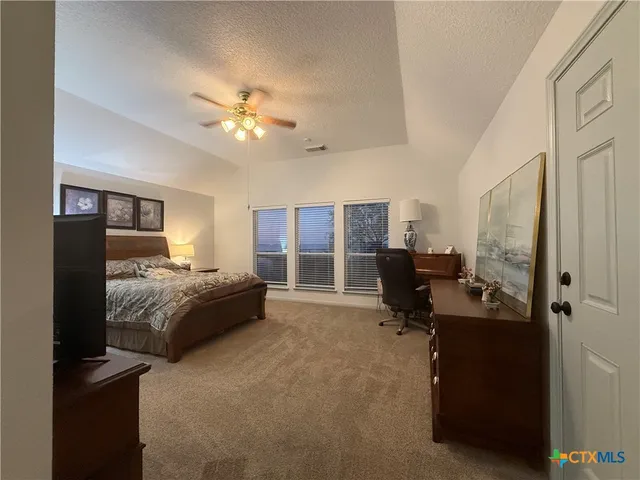 a spacious bedroom with a bed a dresser and large mirror