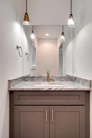 a bathroom with a granite countertop sink a light fixture and a mirror