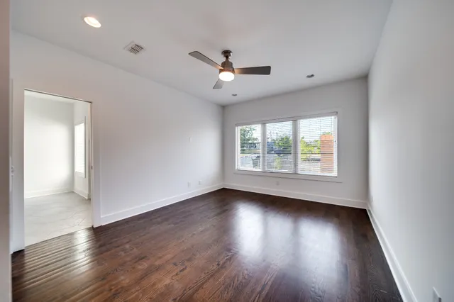an empty room with wooden floor and windows