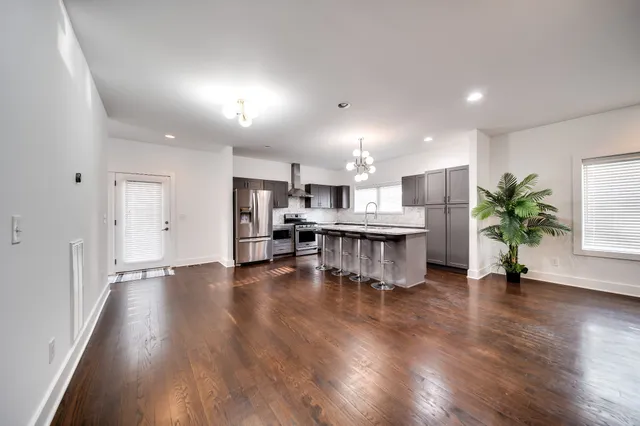 a room with stainless steel appliances kitchen island wooden floors stove and white walls