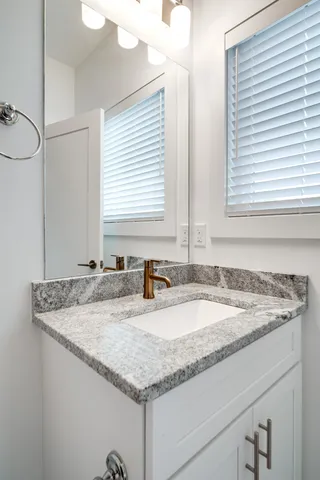 a bathroom with a granite countertop sink and a mirror