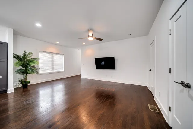 a view of an empty room with wooden floor and a ceiling fan