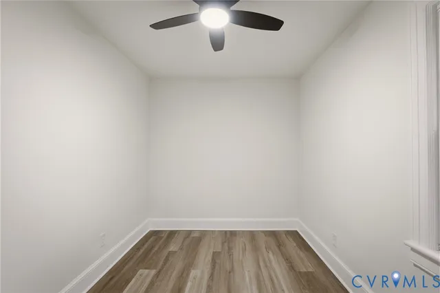 a view of a small space with wooden floor a ceiling fan and table