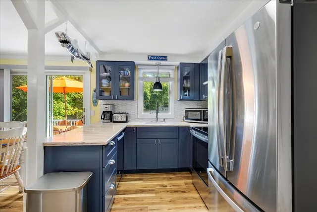 a kitchen with stainless steel appliances granite countertop a refrigerator a sink dishwasher a stove and a dining table with wooden floor