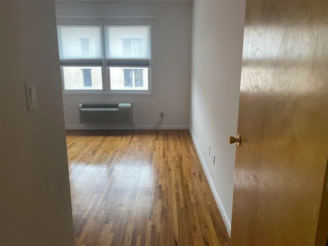 a view of a hallway with wooden floor and a bathroom