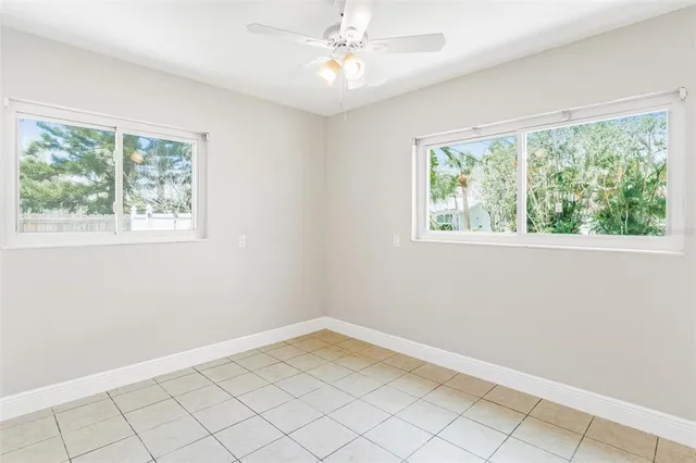 a view of an empty room with window and chandelier fan