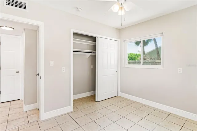 an empty room with chandelier fan and closet area
