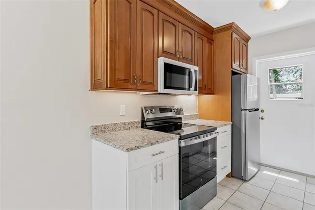 a kitchen with granite countertop a stove top oven microwave and refrigerator