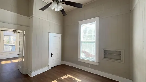 a view of an empty room with wooden floor and a window