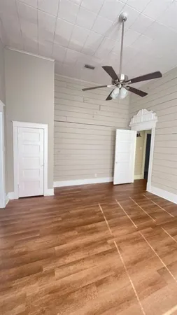 a view of a room with a wooden floor and a ceiling fan