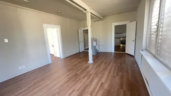 a view of an empty room with wooden floor and a window