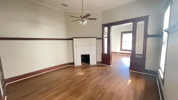 an empty room with wooden floor fireplace and windows