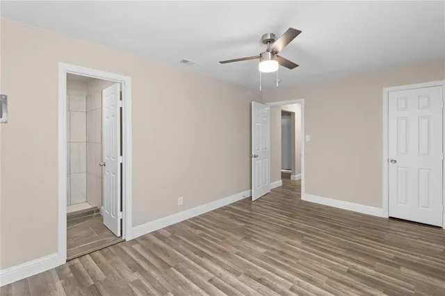 an empty room with wooden floor ceiling fan and windows