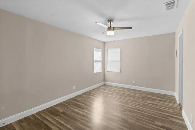 a view of an empty room with wooden floor and a window