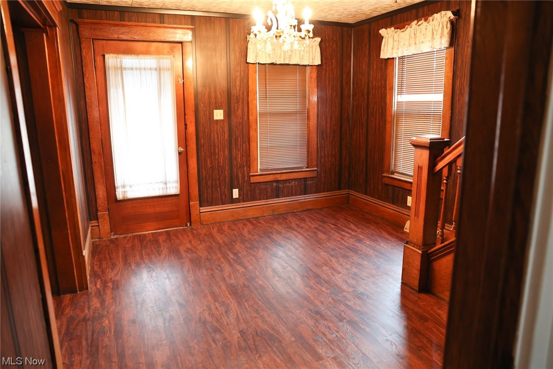1309 Krumroy Road Akron, OH 44306 - Photo 5 of 30 Spare room featuring a chandelier, wooden walls, and dark hardwood / wood-style floors