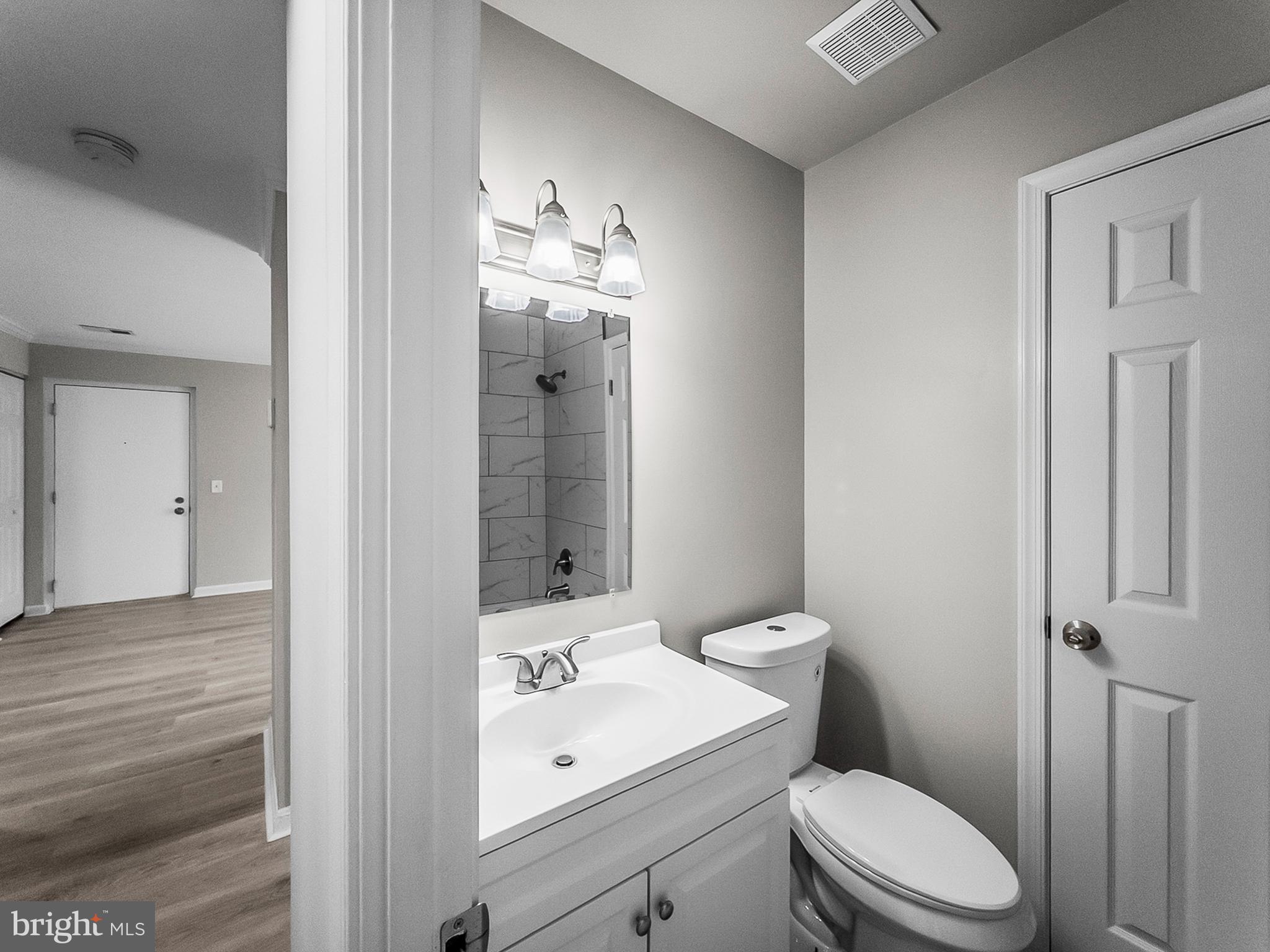 18304 Streamside Drive, Unit 301 Gaithersburg, MD 20879 - Photo 20 of 31 a bathroom with a toilet a sink and mirror