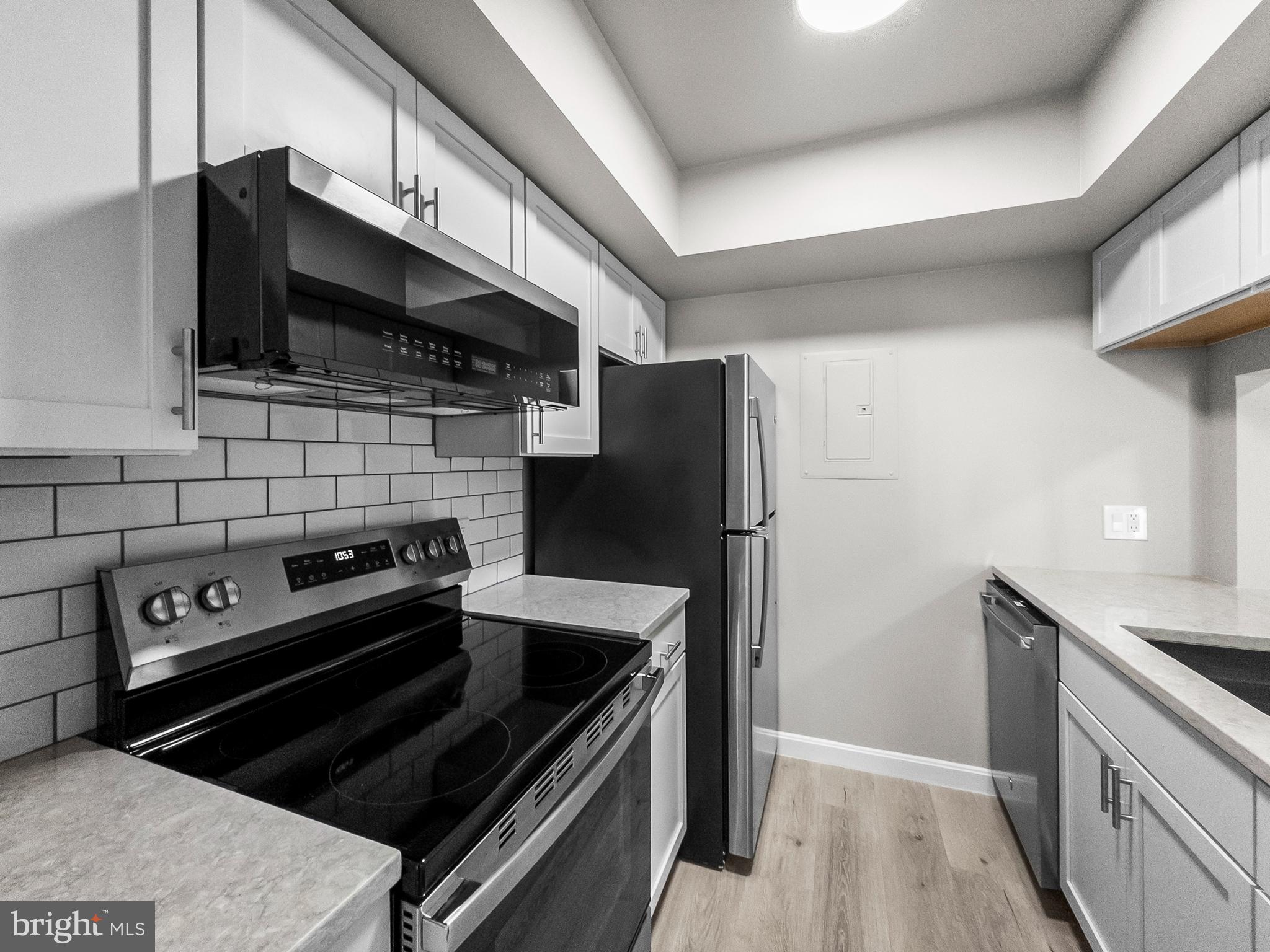 18304 Streamside Drive, Unit 301 Gaithersburg, MD 20879 - Photo 4 of 31 a kitchen with stainless steel appliances and wooden cabinets