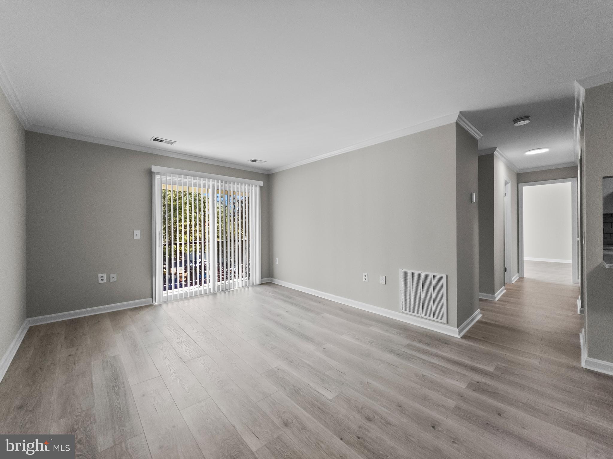 18304 Streamside Drive, Unit 301 Gaithersburg, MD 20879 - Photo 7 of 31 a view of an empty room with wooden floor and a window