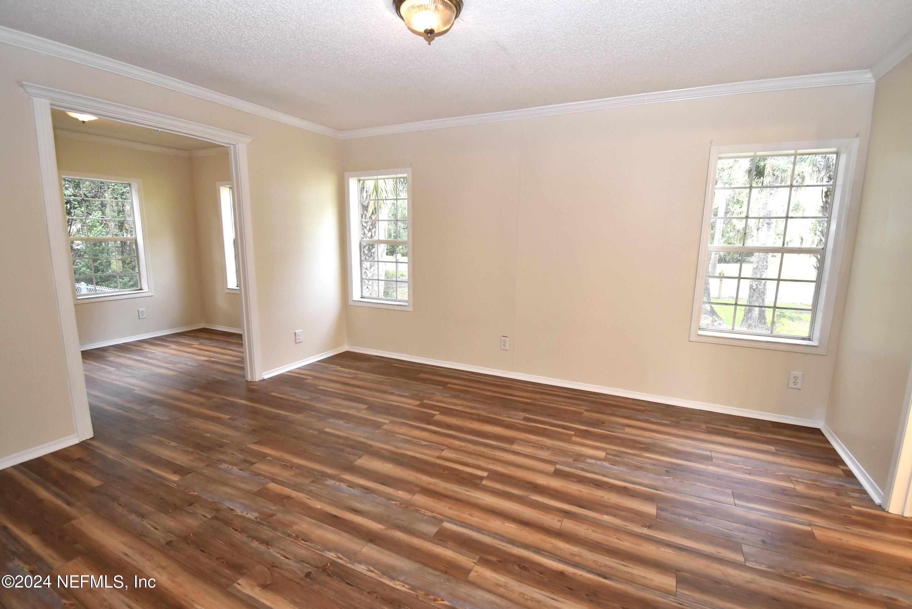 989 Shell Street Welaka, FL 32193 - Photo 16 of 34 an empty room with wooden floor and windows