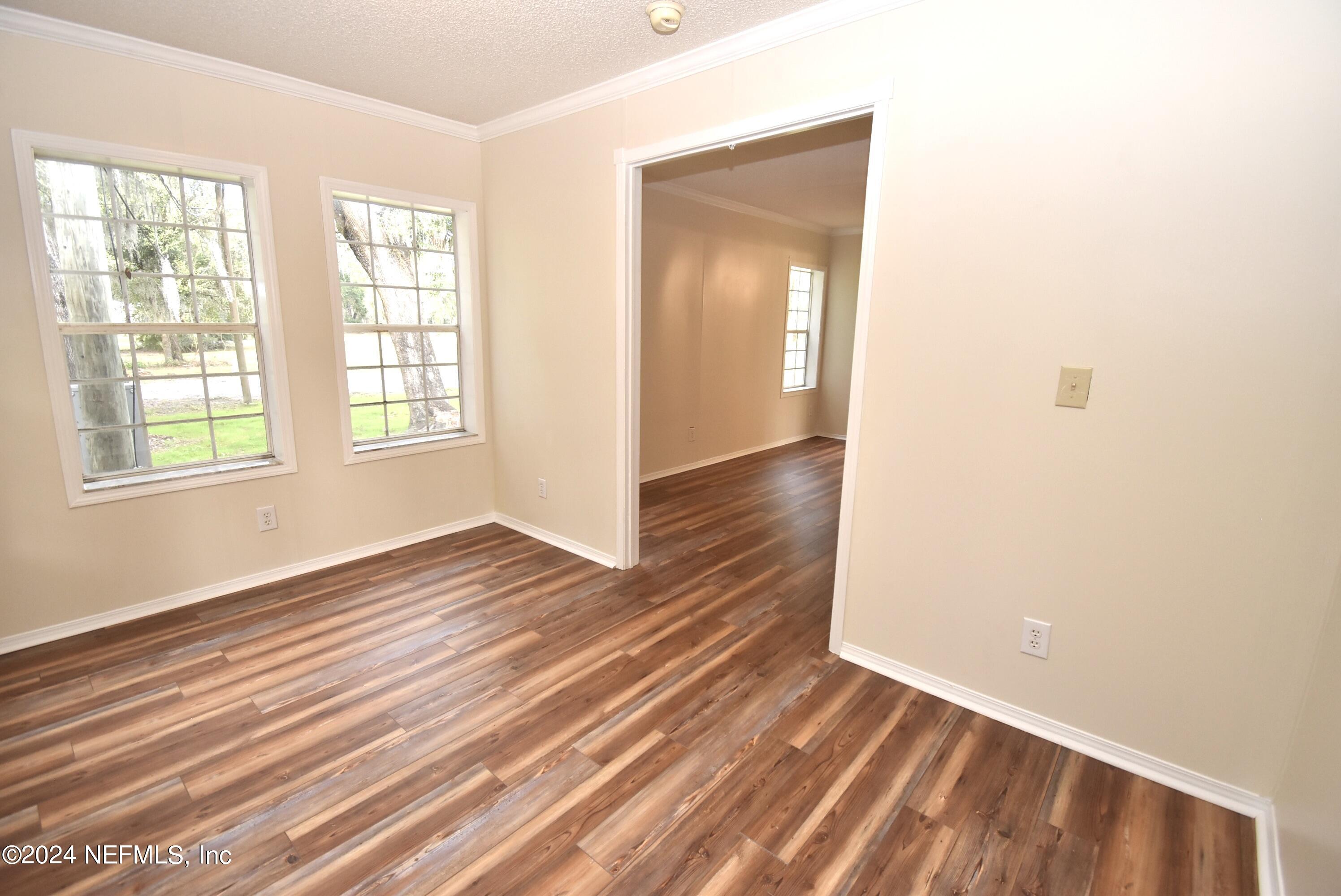 989 Shell Street Welaka, FL 32193 - Photo 19 of 34 an empty room with wooden floor and windows