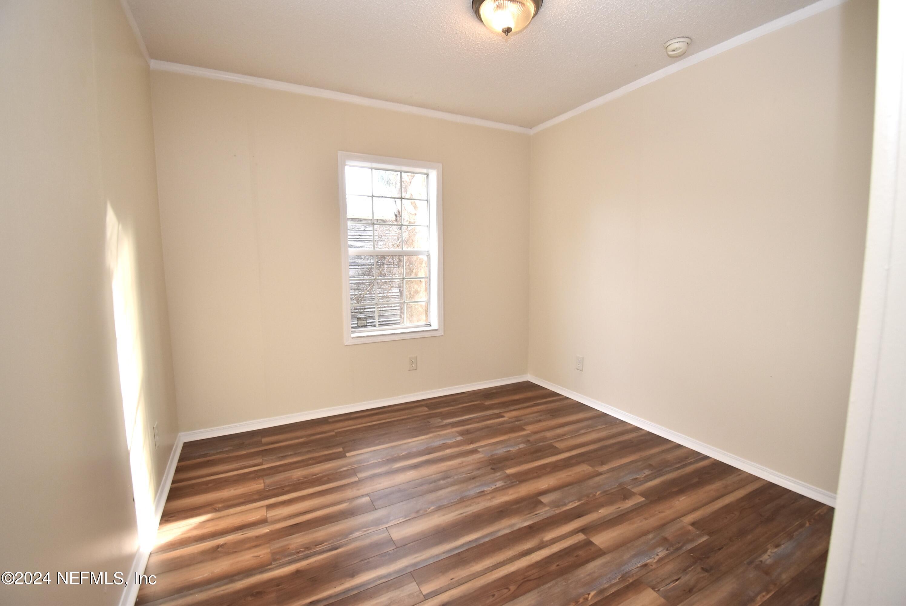 989 Shell Street Welaka, FL 32193 - Photo 26 of 34 an empty room with wooden floor cabinet and windows