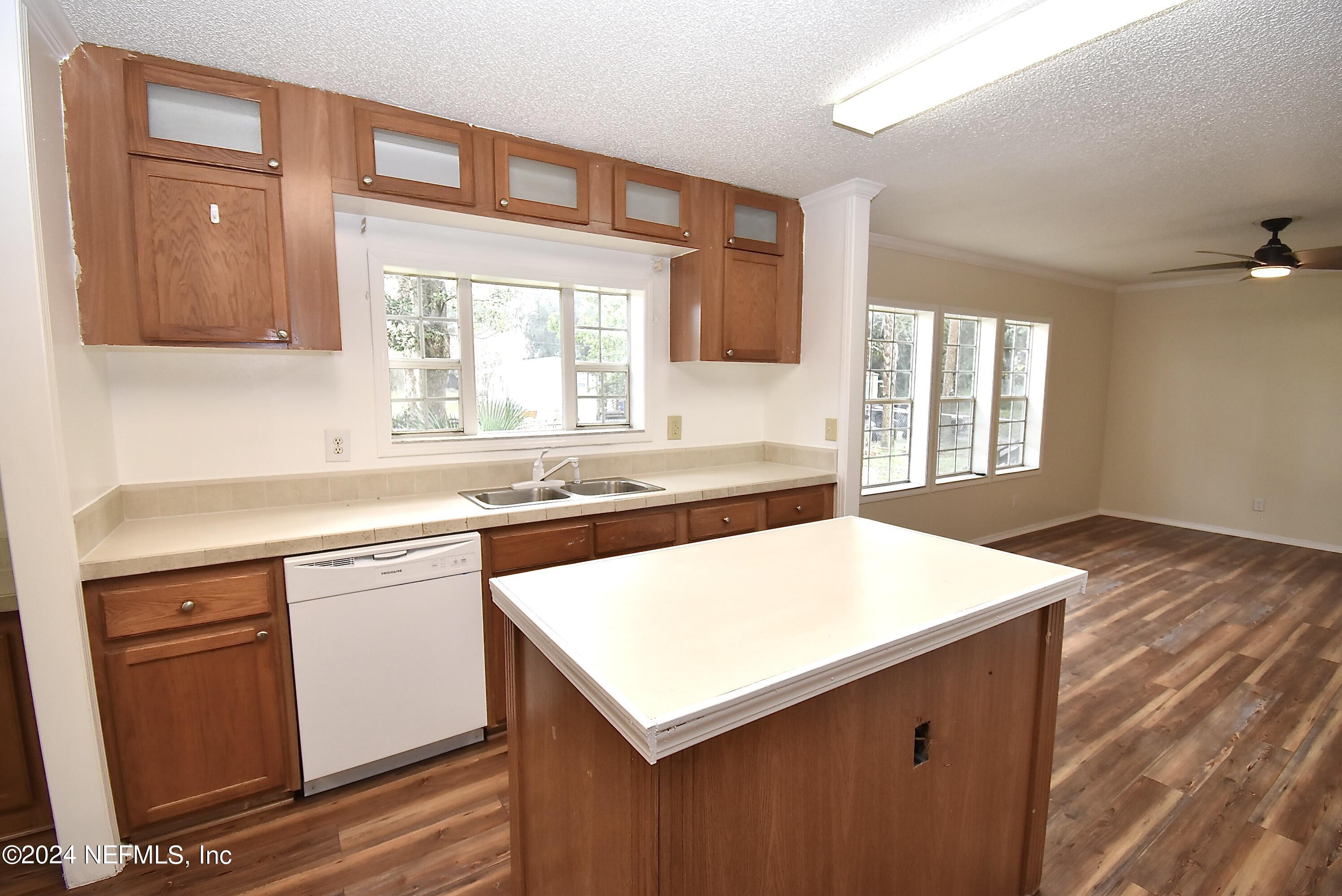 989 Shell Street Welaka, FL 32193 - Photo 10 of 34 a kitchen with a sink dishwasher and white cabinets with wooden floor