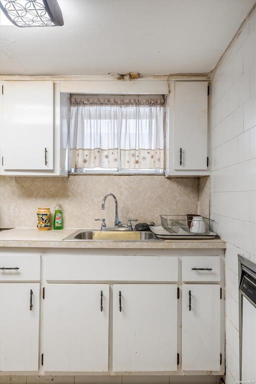 1772 68th Street Brooklyn, NY 11204 - Photo 24 of 34 Kitchen featuring a sink, white cabinets, light countertops, and decorative backsplash