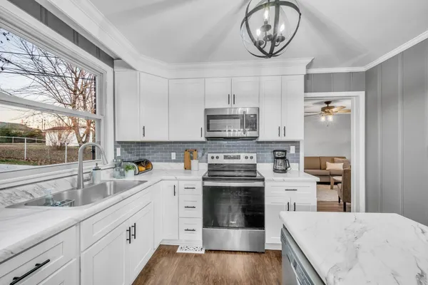 a kitchen with stainless steel appliances granite countertop a stove a sink and a microwave