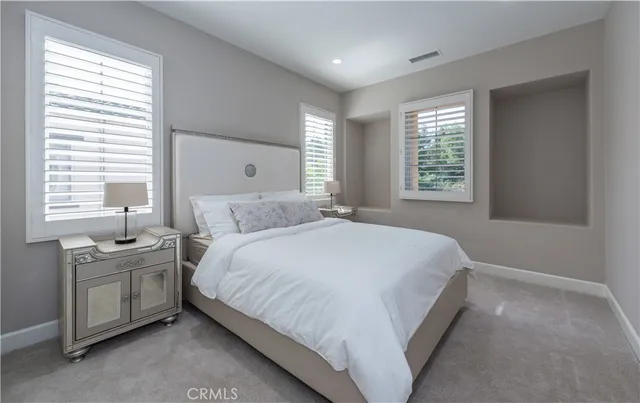 a large bed sitting in a bedroom next to a window and dresser