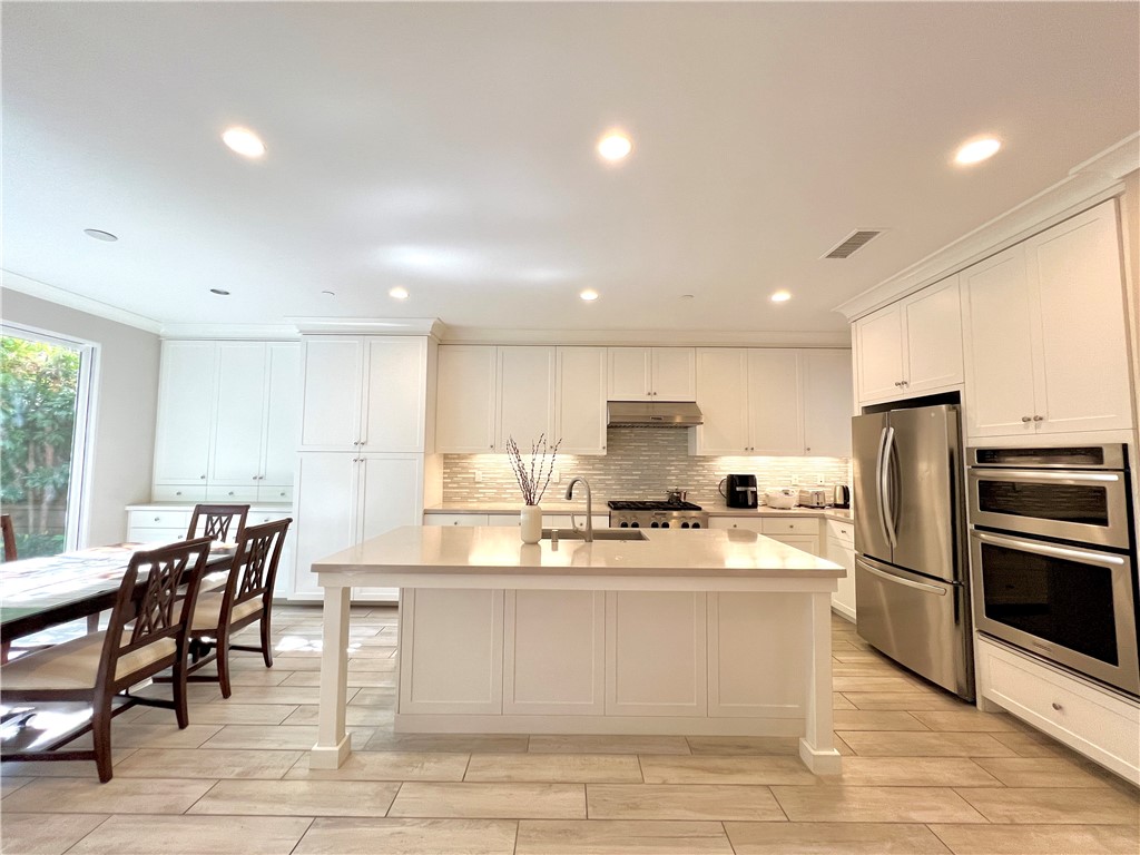 60 Trotter Irvine, CA 92602 - Photo 5 of 24 a open kitchen with stainless steel appliances granite countertop a stove a sink a refrigerator with white cabinets and wooden floor