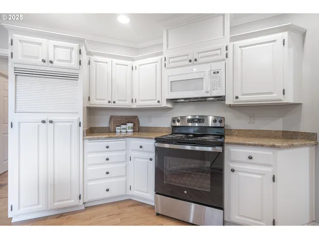 a kitchen with granite countertop white cabinets and stainless steel appliances