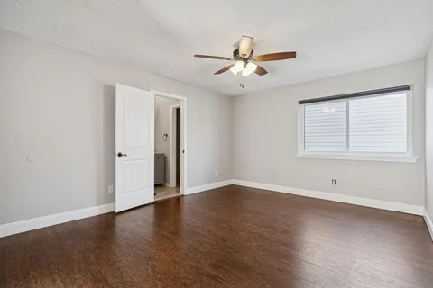 an empty room with wooden floor fan and windows