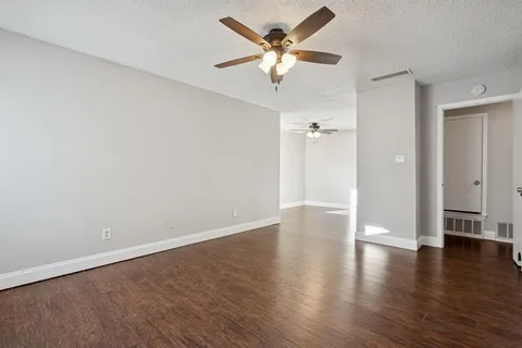 an empty room with wooden floor and ceiling fan