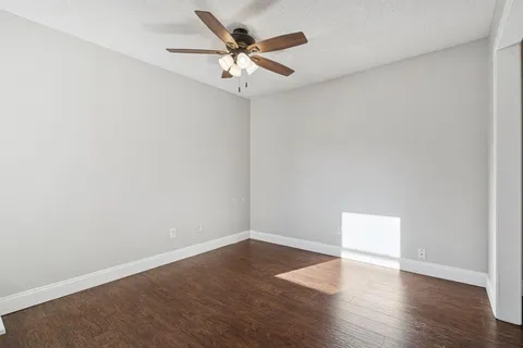 an empty room with wooden floor and ceiling fan