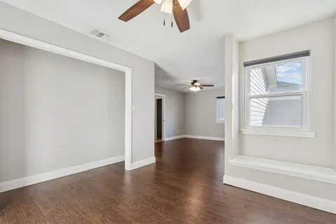 an empty room with wooden floor cabinet and windows