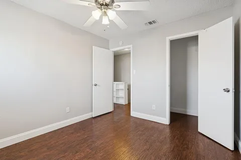an empty room with wooden floor and ceiling fan