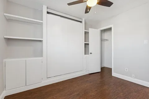 an empty room with wooden floor closet ceiling fan and windows