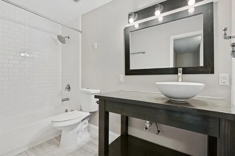 a bathroom with a sink a toilet a mirror and shower