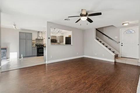 a view of an empty room with wooden floor and a ceiling fan